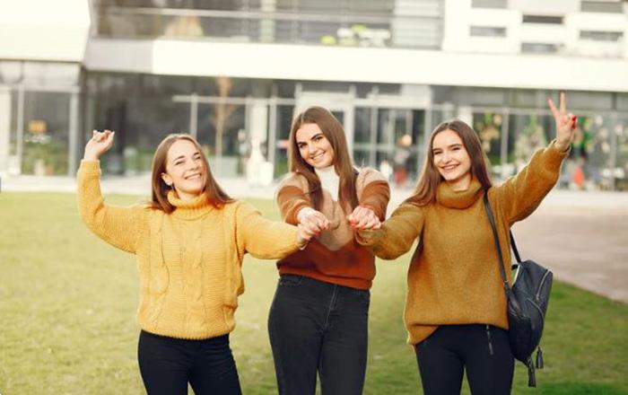 Tre studentesse che sorridono e si tengono per mano
